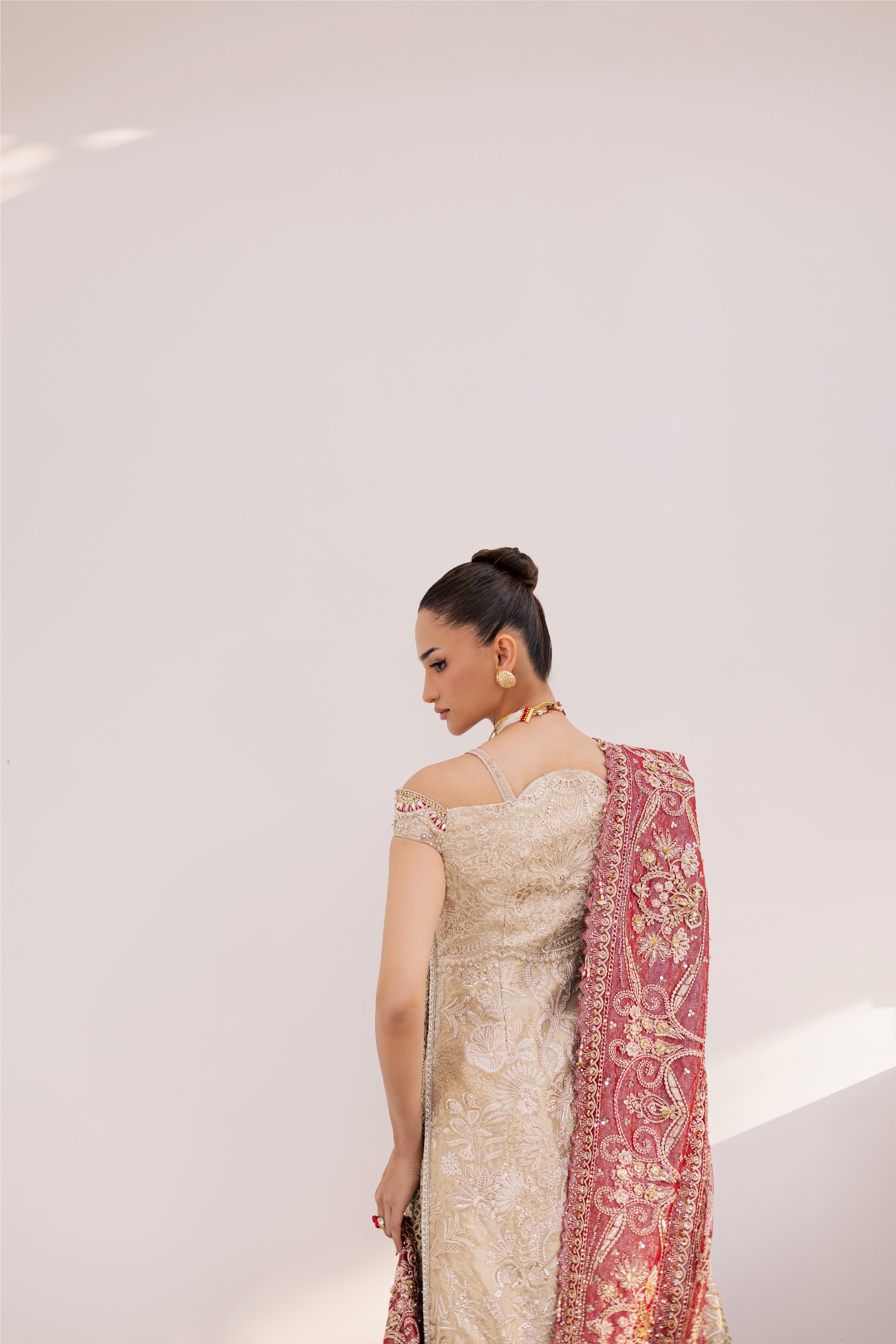 Model wearing champagne gold hand-embellished shirt and lehenga with rich maroon dupatta, luxury Pakistani couture by Mysie by Tahira.