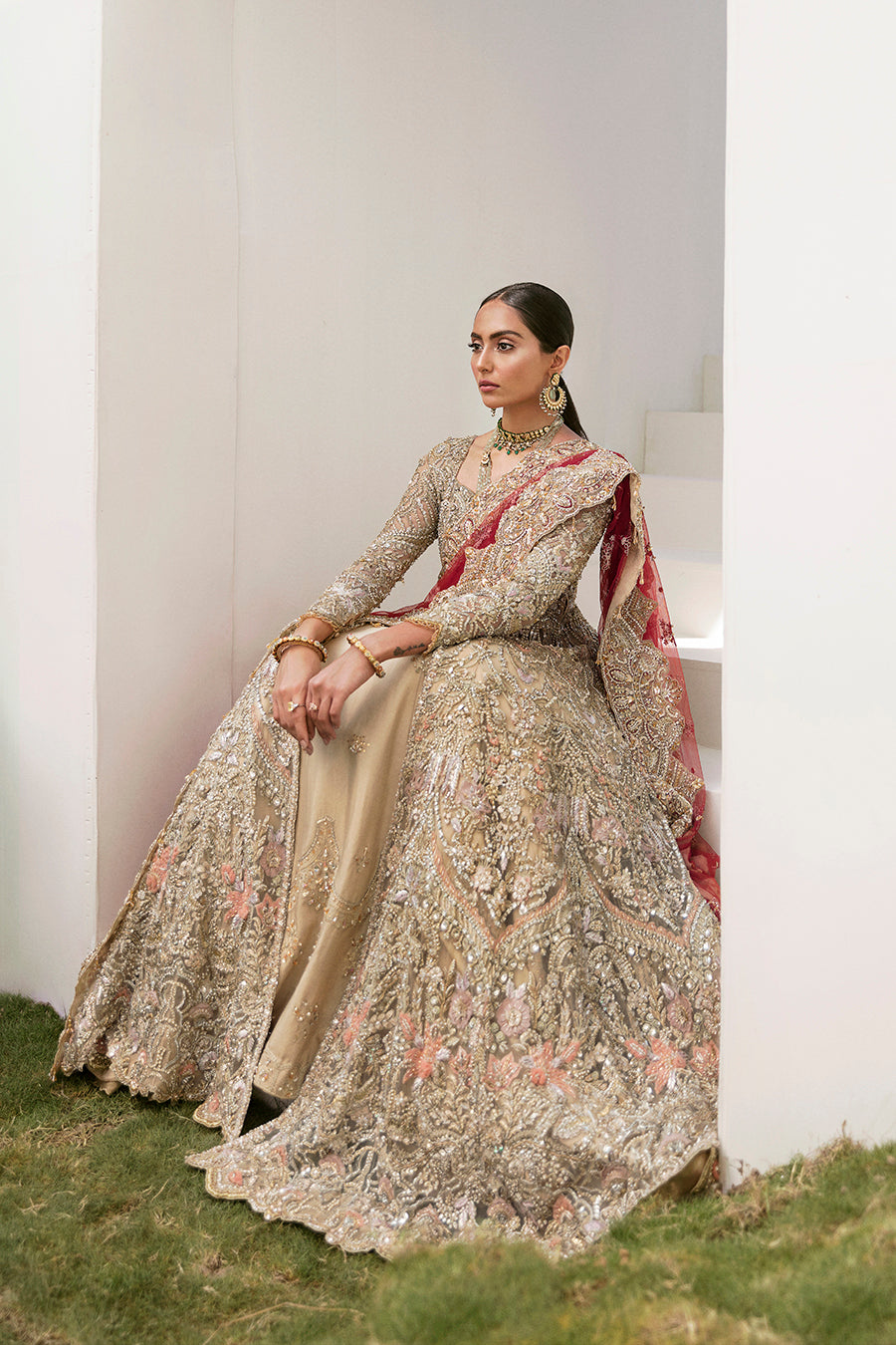 Elegant Gaia bridal gown in gold with intricate embroidery, paired with a red dupatta and raw-silk lehenga.
