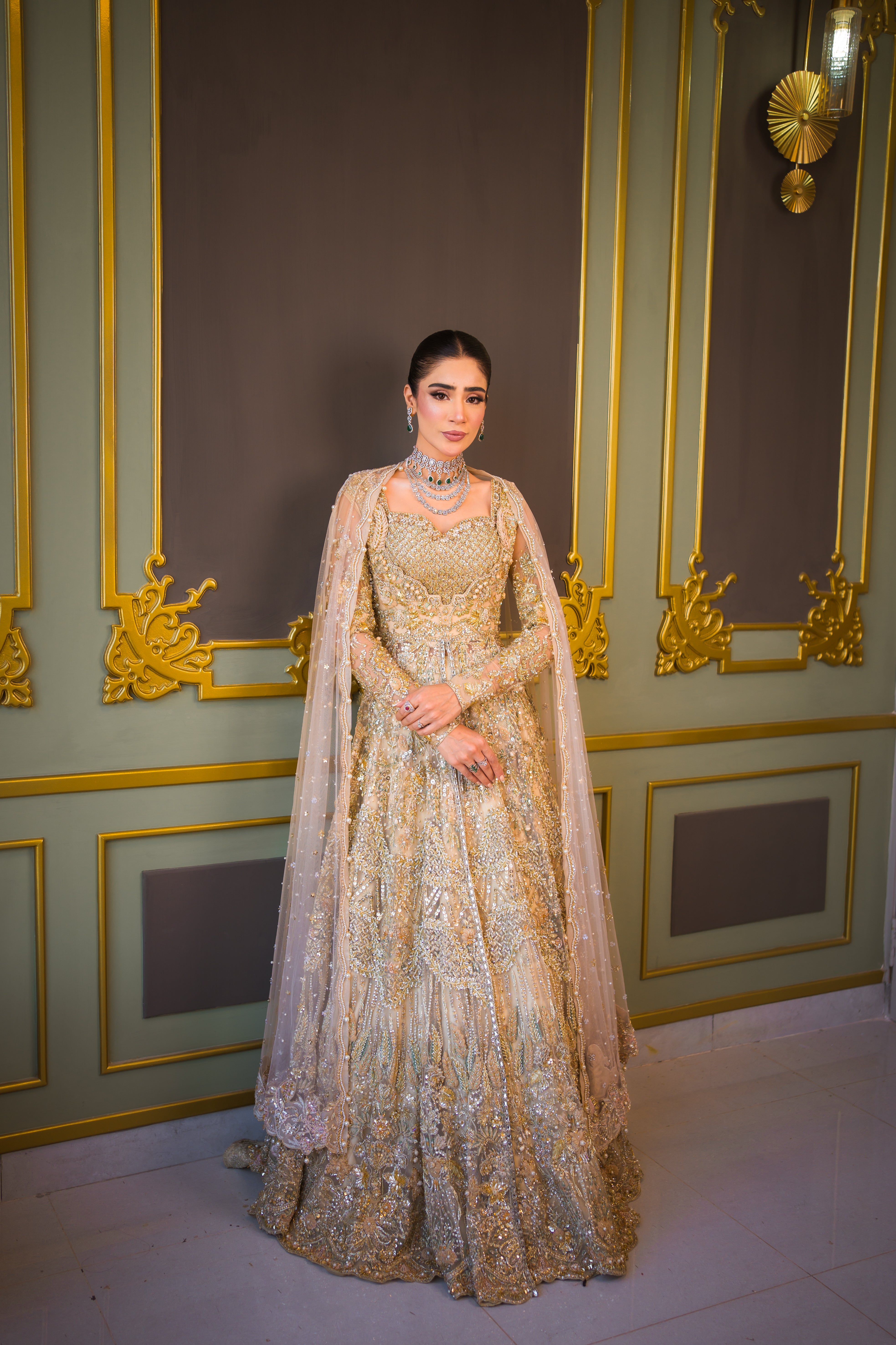 Luxury Pakistani bridal outfit Biana in subtle gold net fabric with hand embellishments.
