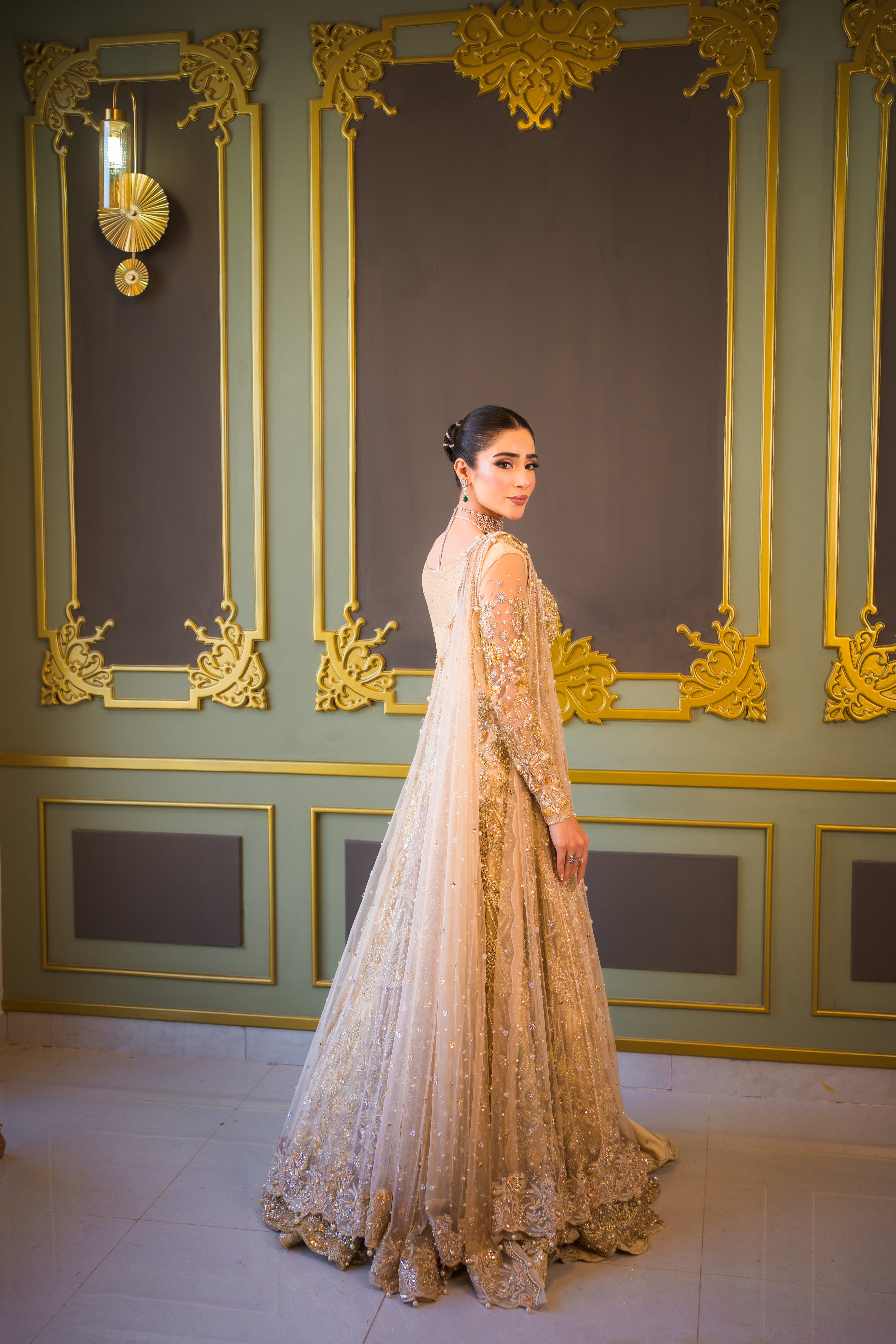 Luxury Pakistani bridal outfit Biana in subtle gold net fabric with hand embellishments.