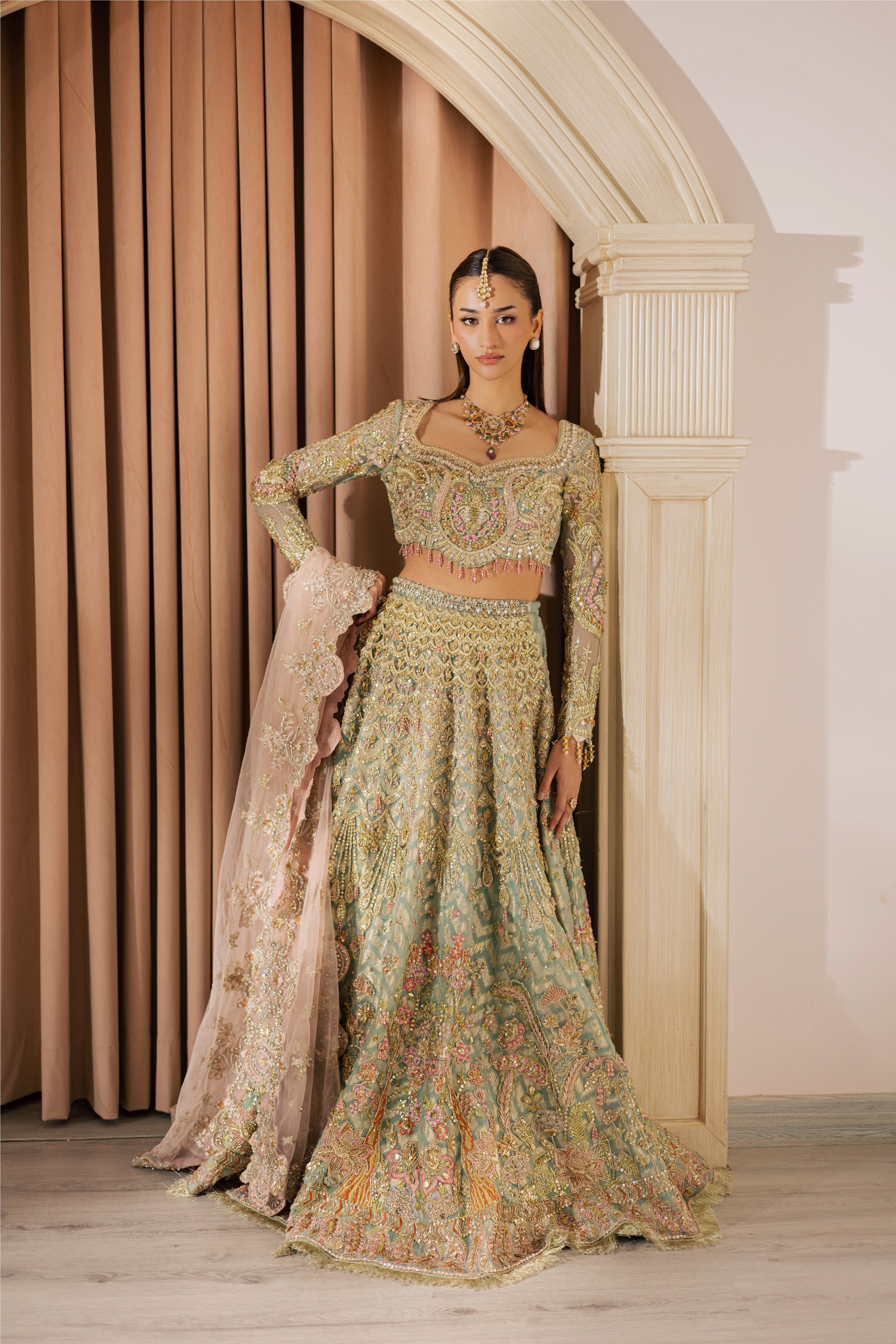 Luxury gold and pastel net Pakistani bridal lehenga by Mysie by Tahira, featuring intricate hand embellishment and couture detailing.