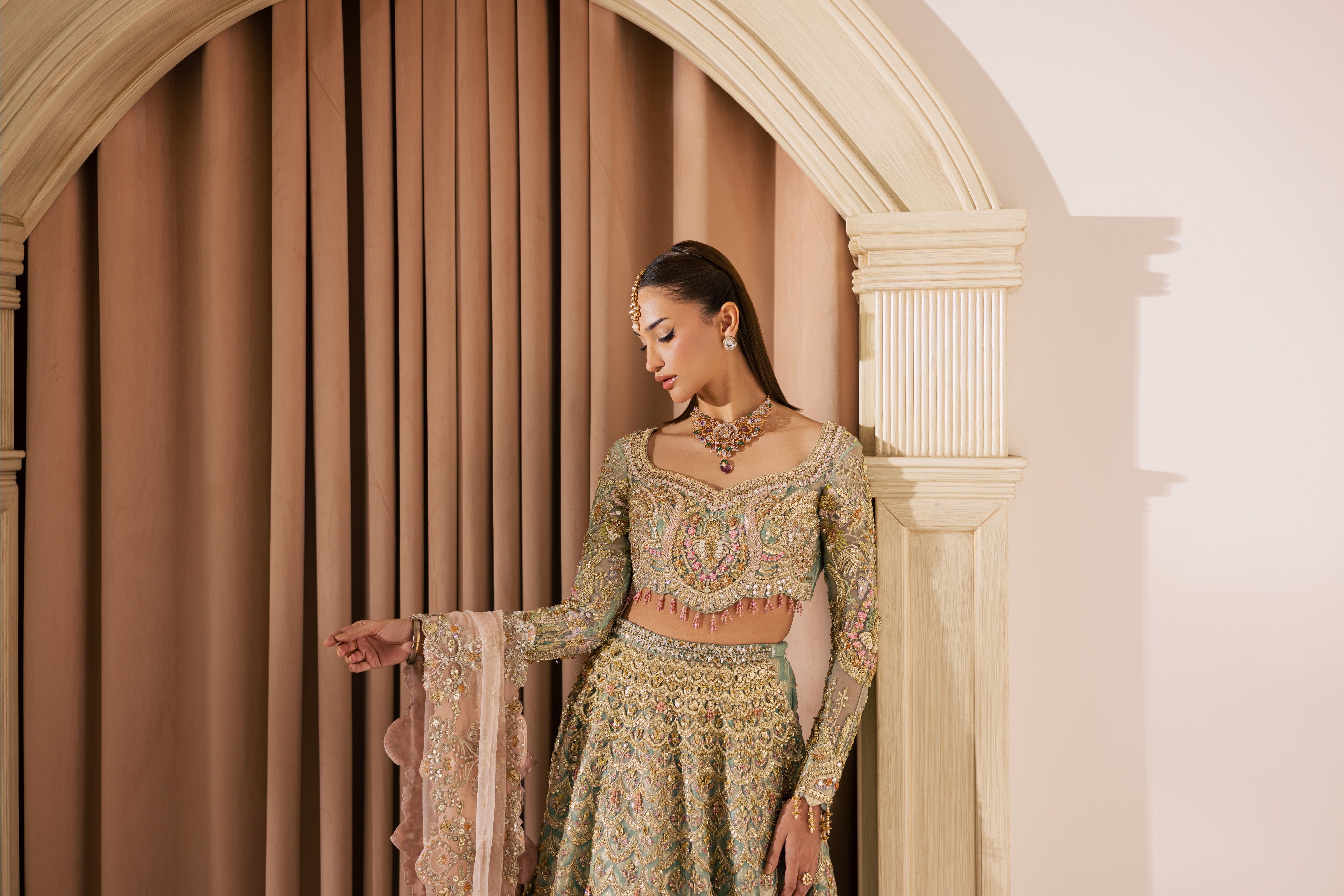 Luxury gold and pastel net Pakistani bridal lehenga by Mysie by Tahira, featuring intricate hand embellishment and couture detailing.