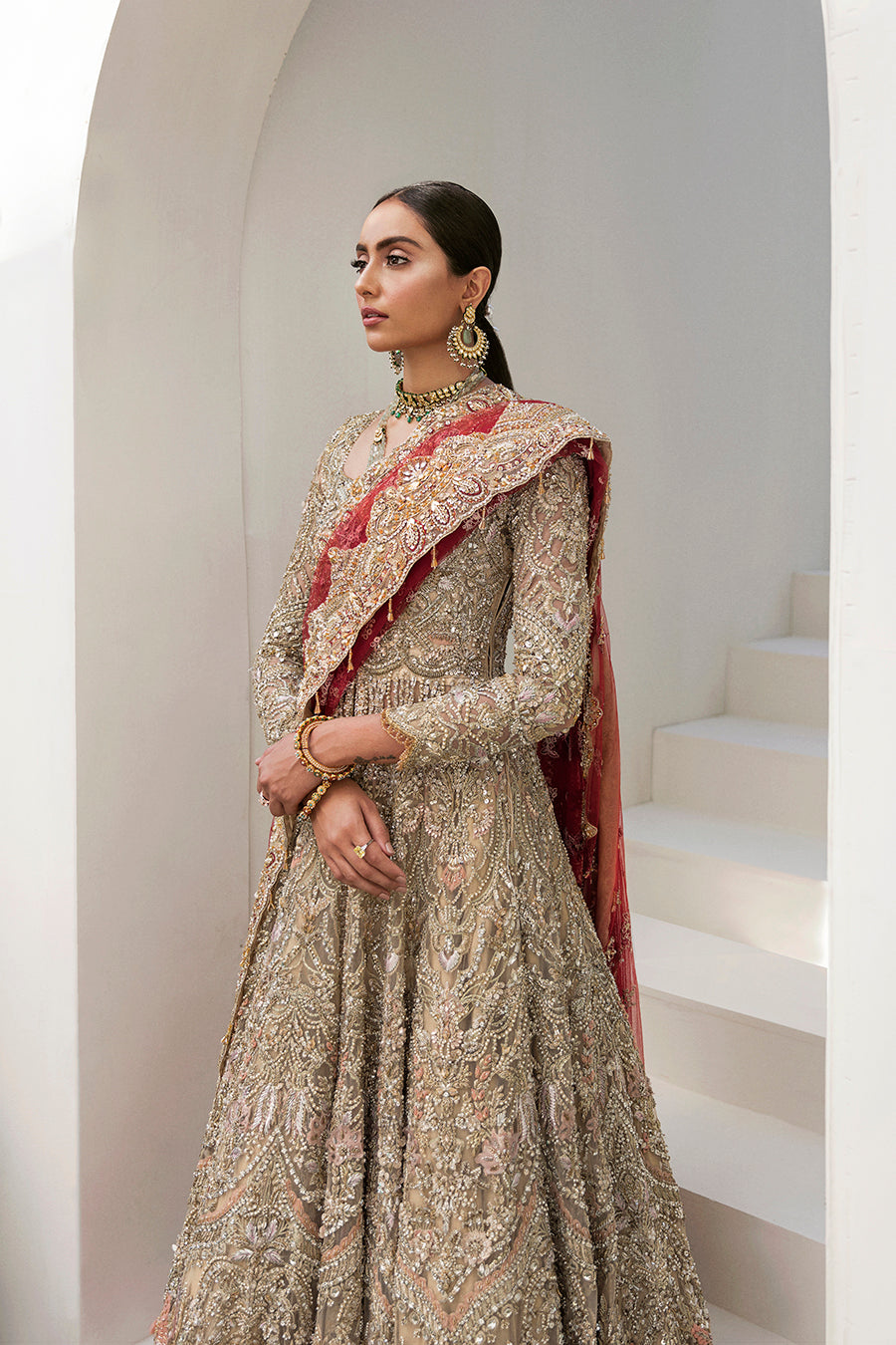 Elegant Gaia bridal gown in gold with intricate embroidery, paired with a red dupatta and raw-silk lehenga.